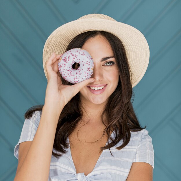 Beautiful lady covering her eye with a donut