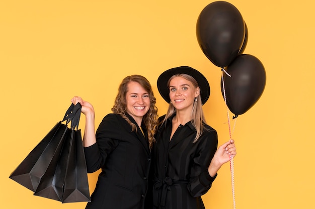 Beautiful lady friends holding shopping bags and balloons