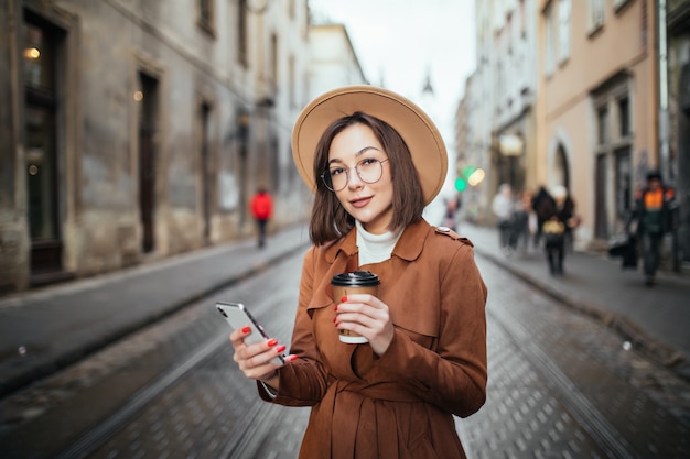 Beautiful lady has a videocall and drinks coffee while walking outdoors in the city