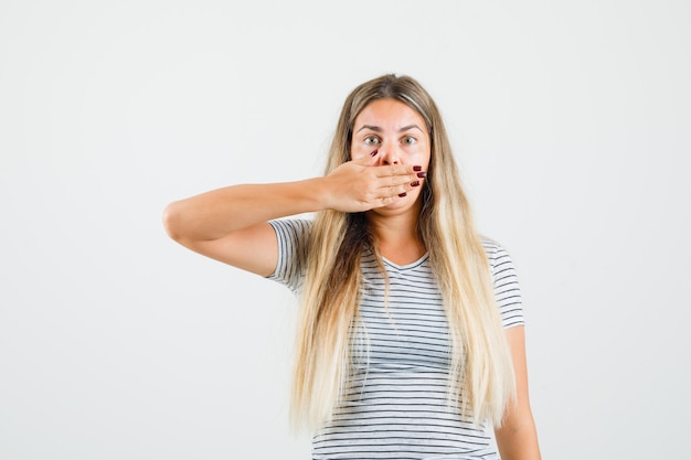 Beautiful lady holding hand on her mouth in t-shirt and looking quiet. front view.