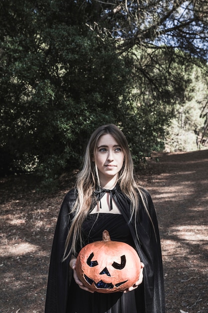 Bella signora che tiene la zucca nel parco