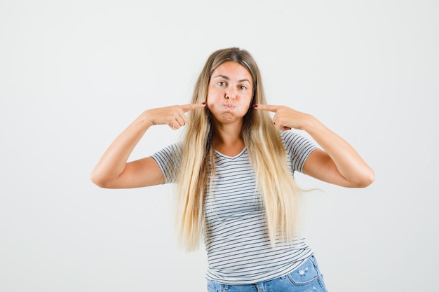 Beautiful lady inflating her cheeks in t-shirt and looking funny. front view.