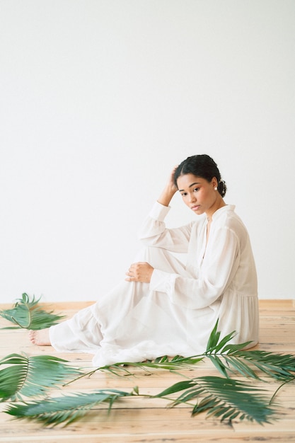 Beautiful lady in long white dress sitting and looking in empty room . space for text