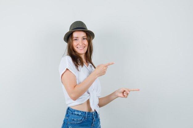 Beautiful lady pointing aside in white blouse,hat and looking jolly , front view.