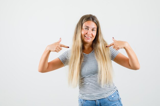 Beautiful lady pointing at herself in t-shirt and looking jolly. front view.