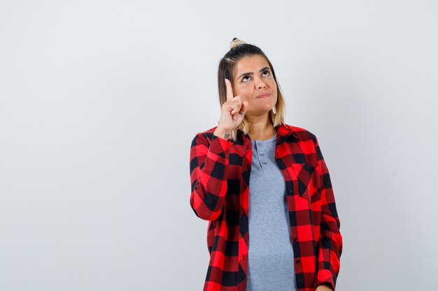 Beautiful lady pointing up, looking upward in casual clothes and looking hopeful. front view.