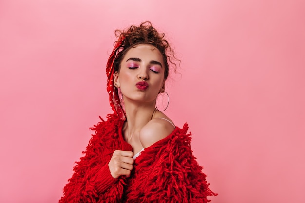 Beautiful lady in red coat blowing kiss on pink