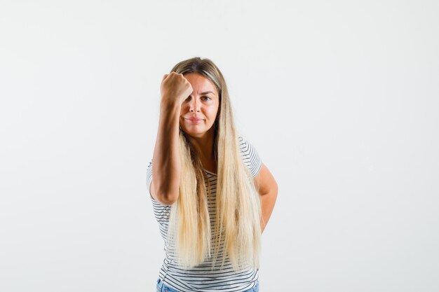 Beautiful lady showing her fist in t-shirt and looking powerful , front view.