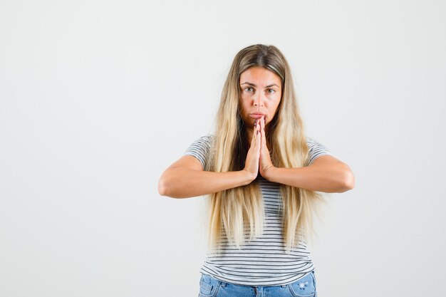 Beautiful lady showing namaste gesture in t-shirt front view.