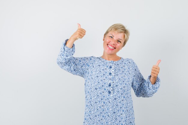 Beautiful lady showing thumb up in patterned blouse and looking happy. front view.