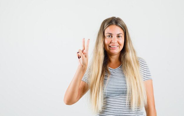 Beautiful lady showing v-sign in t-shirt and looking jolly , front view.