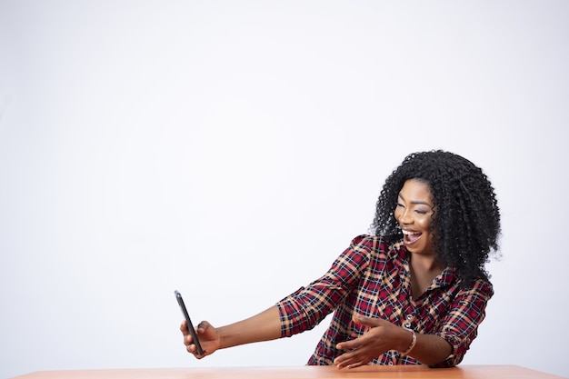 Bella signora seduta utilizzando il suo telefono, guardando sorpreso ed emozionato