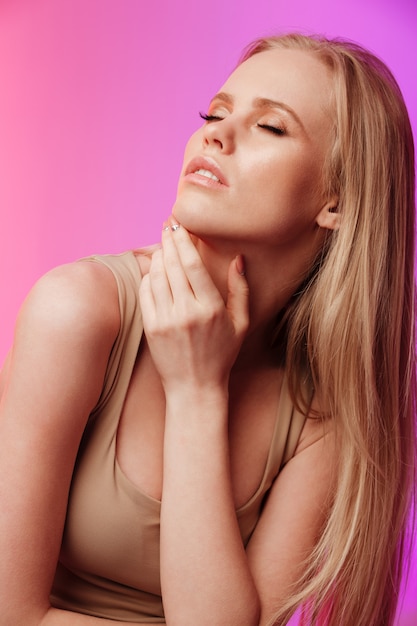 Beautiful lady standing and posing over pink wall