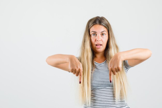 Beautiful lady in t-shirt pointing down and looking concentrated , front view.