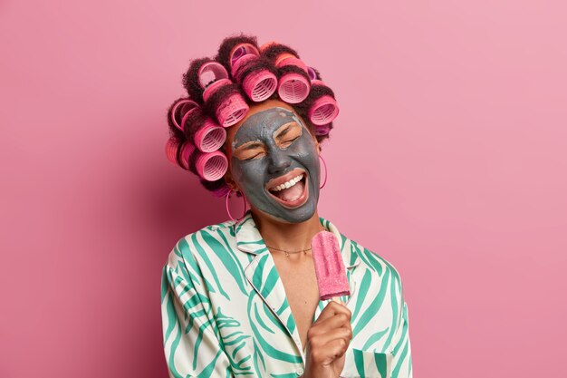 Beautiful lady wearing mask for face care wearing hair curlers isolated