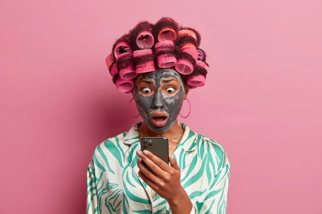 Beautiful lady wearing mask for face care wearing hair curlers isolated