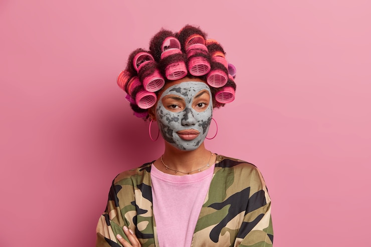 Free Photo beautiful lady wearing mask for face care wearing hair curlers isolated