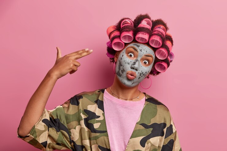 Free Photo beautiful lady wearing mask for face care wearing hair curlers isolated
