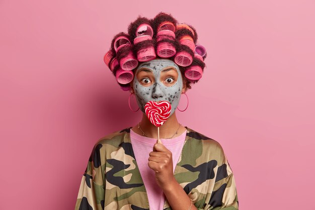 Beautiful lady wearing mask for face care wearing hair curlers isolated