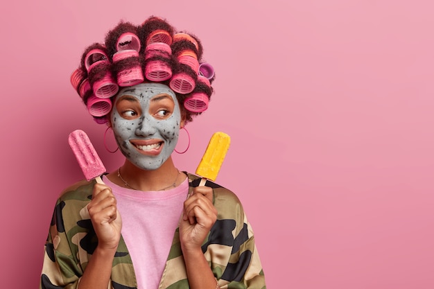 Beautiful lady wearing mask for face care wearing hair curlers isolated