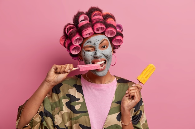 Beautiful lady wearing mask for face care wearing hair curlers isolated