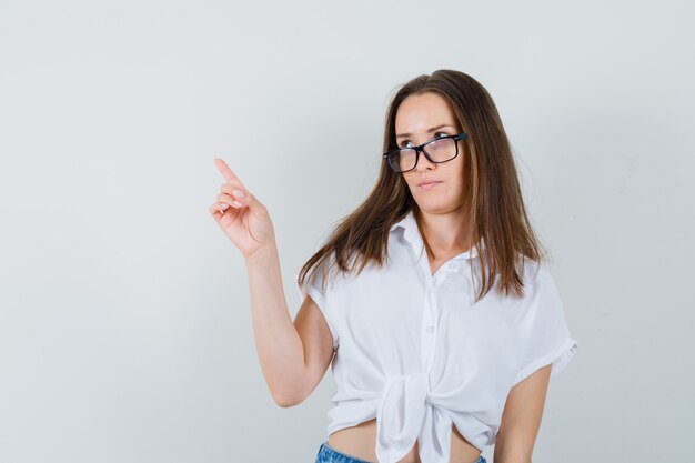 Beautiful lady in white blouse,glasses pointing back , front view.