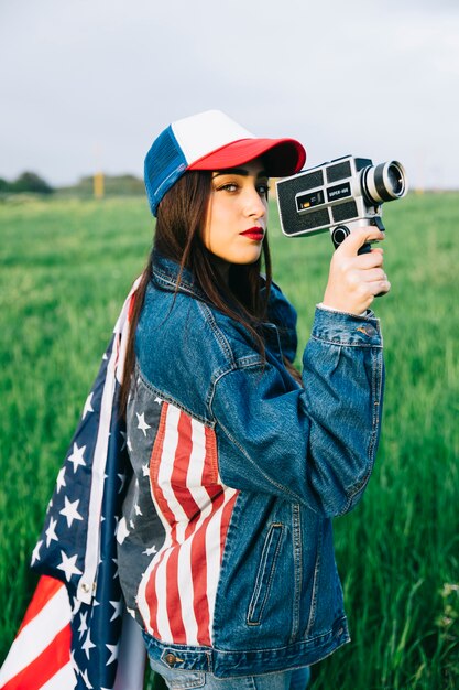 Beautiful lady with retro camera staying in field