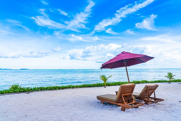 Beautiful landscape of beach sea ocean with empty chair deck and umbrella nearly coconut palm tree with white cloud and blue sky