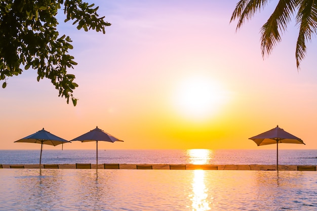 Bellissimo paesaggio piscina all'aperto con ombrellone e sdraio in hotel resort per relax tra