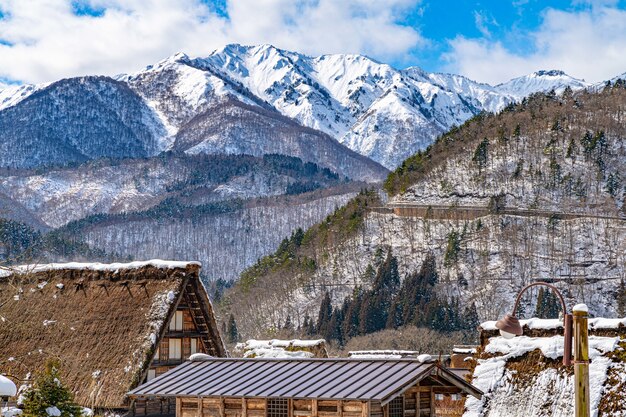 일본의 마을 지붕, 소나무 및 눈 덮힌 산의 아름다운 풍경
