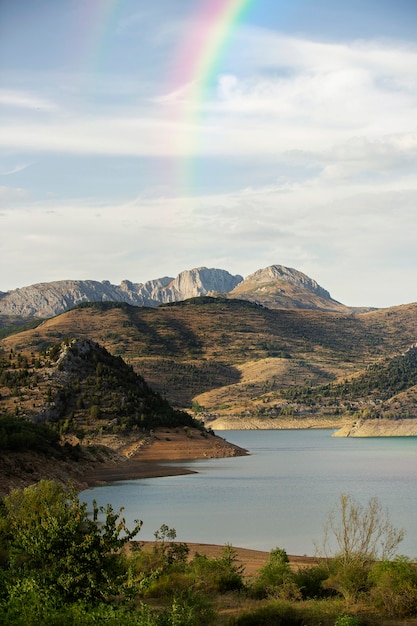 Foto gratuita bellissimo paesaggio con arcobaleno e colline