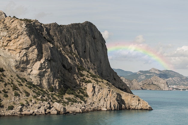 Foto gratuita bellissimo paesaggio con arcobaleno e roccia
