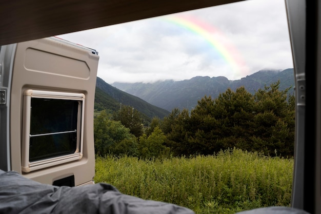 Foto gratuita bellissimo paesaggio con arcobaleno e furgone