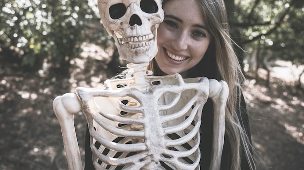 Free photo beautiful laughing woman behind skeleton