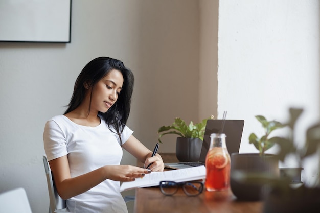 メモを取るカフェで勉強している美しい左利きの女の子私は