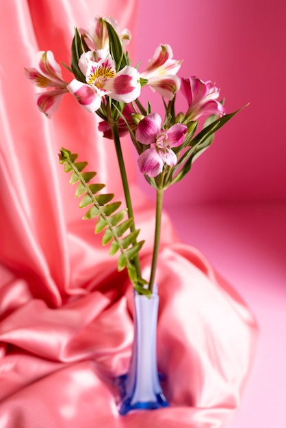 Free photo beautiful lilies in vase with pink cloth
