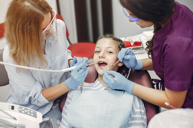 Красивая маленькая девочка сидит в кабинете стоматолога
