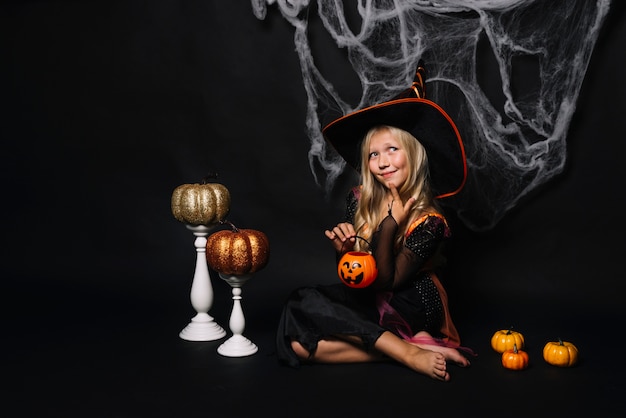 Free photo beautiful little witch with jack-o-lantern