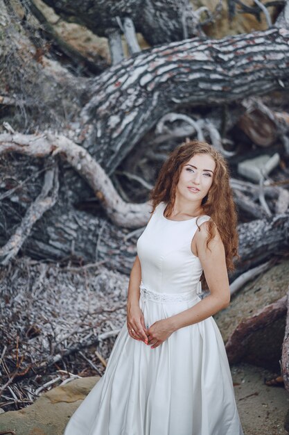 Beautiful long-haired bride in a magnificent white dress in nature