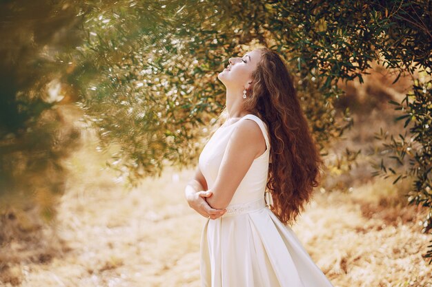 自然で歩く壮大な白いドレスの美しい長髪の花嫁