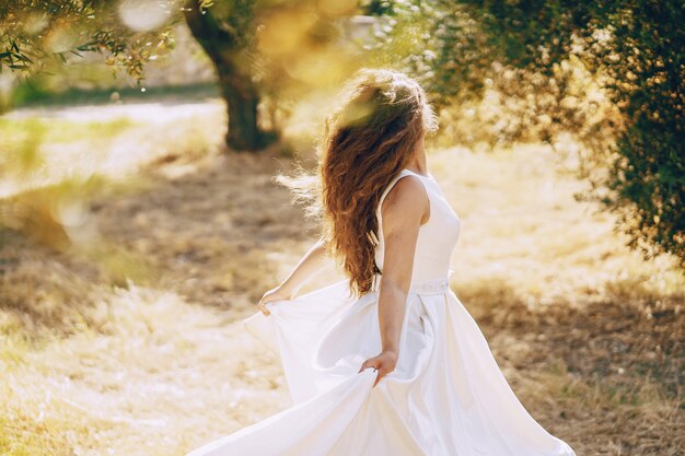 자연 속에서 걷는 웅장한 하얀 드레스를 입고 아름다운 긴 머리 신부