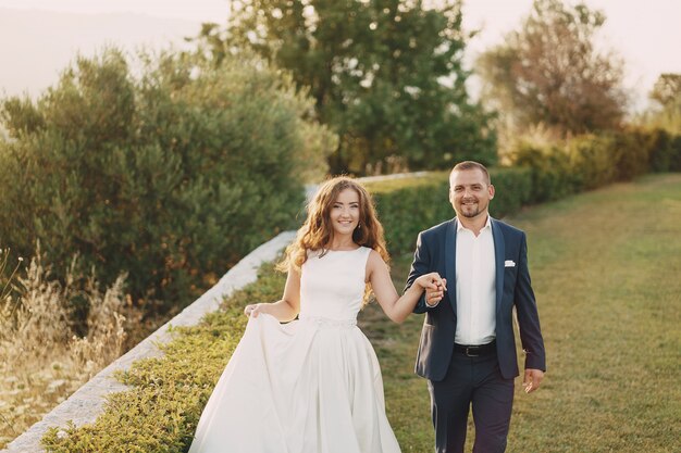 beautiful long-haired bride in white dress with her young man walking in the nature