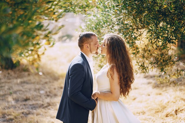 beautiful long-haired bride in white dress with her young man walking in the nature