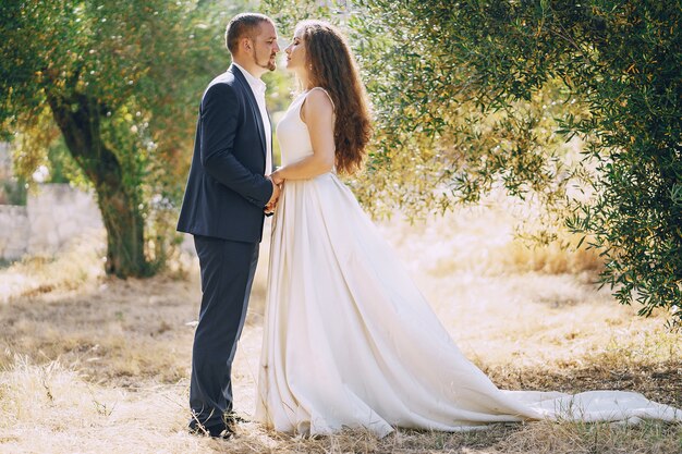 beautiful long-haired bride in white dress with her young man walking in the nature