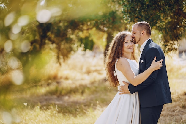 beautiful long-haired bride in white dress with her young man walking in the nature