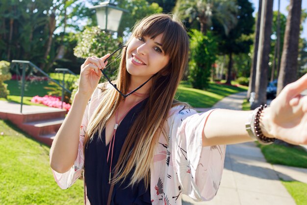 Beautiful long haired woman with  trendy hairstyle making self portrait