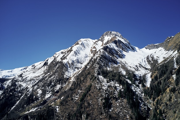 Beautiful low angle shot of a mountain with snow covering the peak and the sky in the