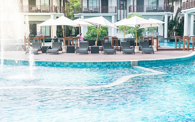 우산과 의자가있는 아름다운 고급 호텔 수영장 리조트