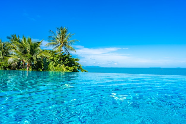 Красивый роскошный открытый бассейн в курортном отеле с морским океаном вокруг кокосовой пальмы и белого облака на голубом небе