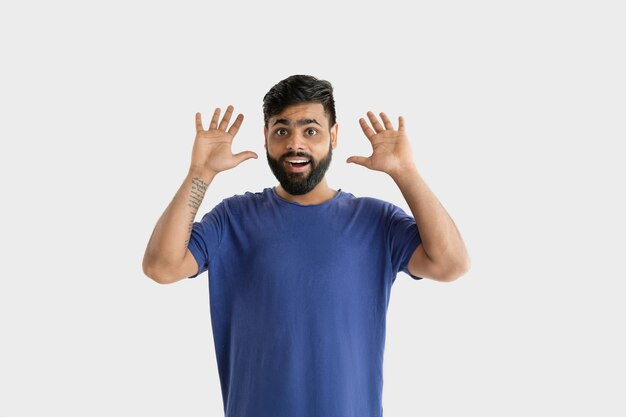 Beautiful male half-length portrait isolated on white studio background. Young emotional hindu man in blue shirt. Facial expression, human emotions, ad concept. Astonished, shocked, crazy happy.